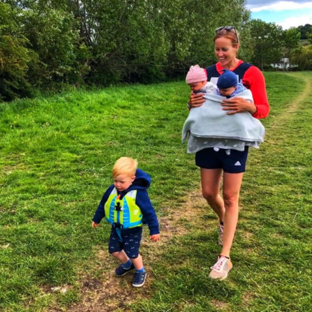 Helen walks along a path with her twins carried on her chest, as her young son logan runs ahead in blue shorts and a life jacket