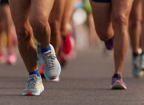 A close-up of people's legs and running shoes while running